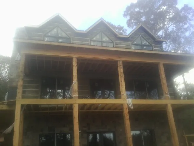 Dormers and porch framing on a large log home under construction — Roof Coating work by our crew in Driggs