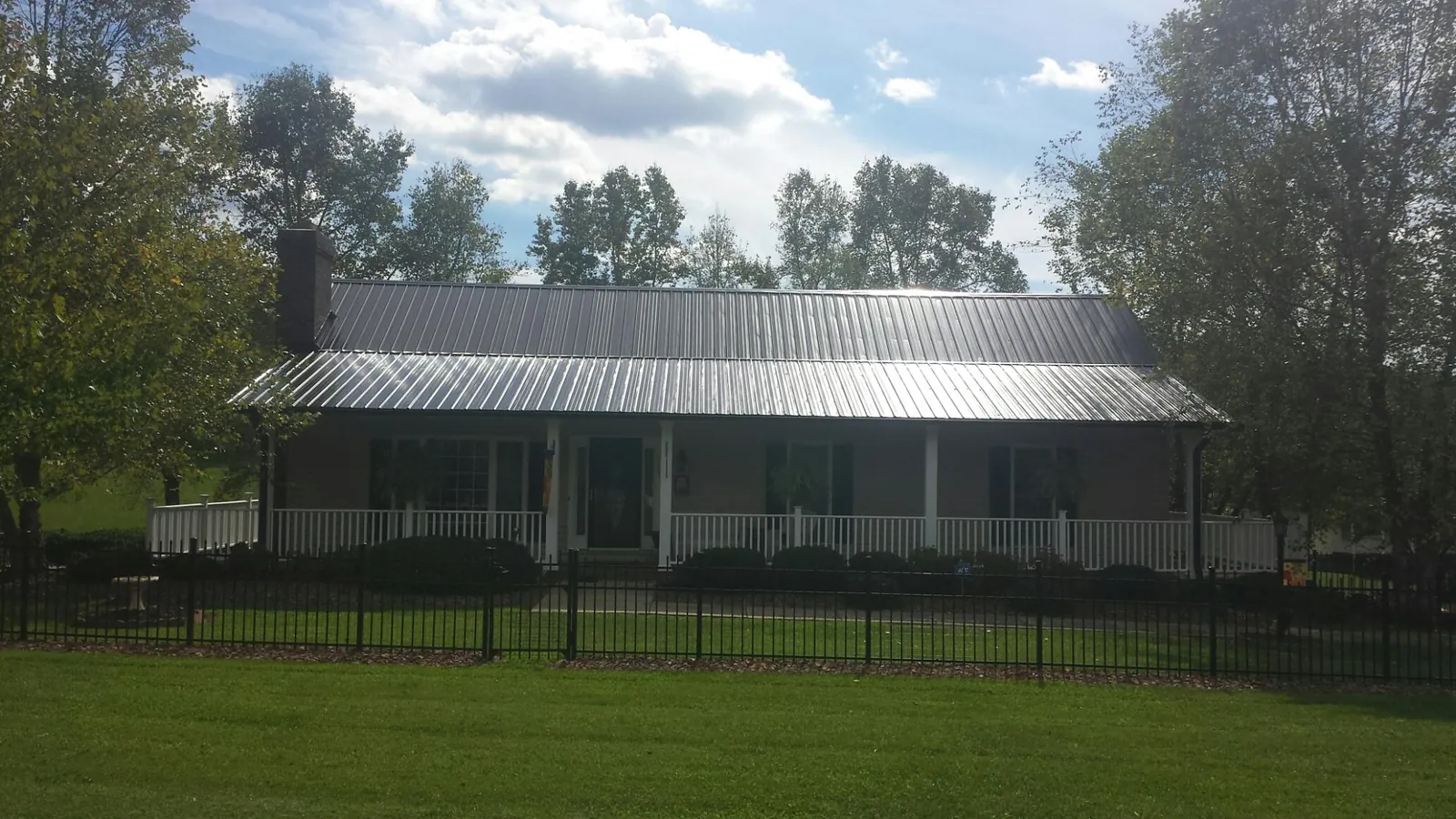 Gray metal roof on a brick ranch with a full width front porch — Gutter Guard Installation work by our crew in Driggs