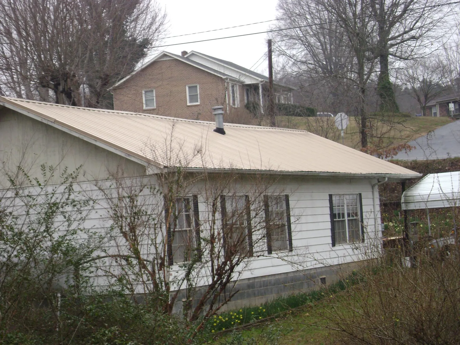 Tan metal roof on a white sided house set into a hillside — Commercial Roofing by Roofing Brothers in Driggs