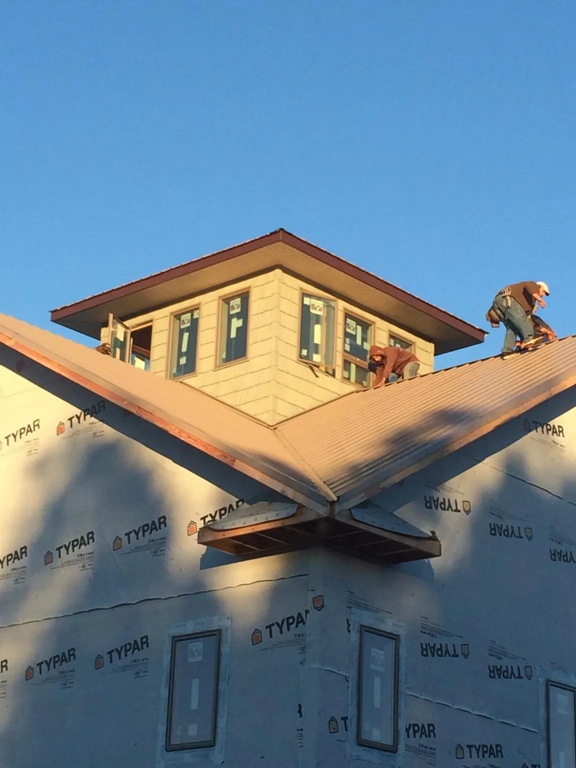 Roofers working around a rooftop cupola on a new metal roof at sunset — Roof Waterproofing in Driggs by Roofing Brothers